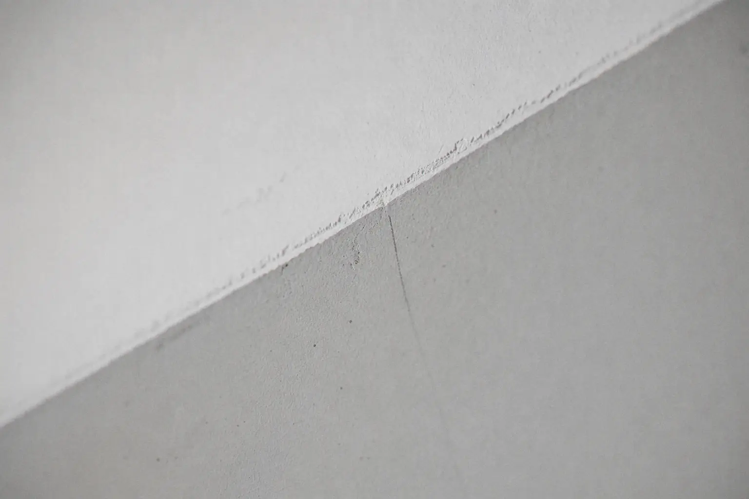 Arête nette entre un plafond blanc pur et un mur gris soie fraîchement peints