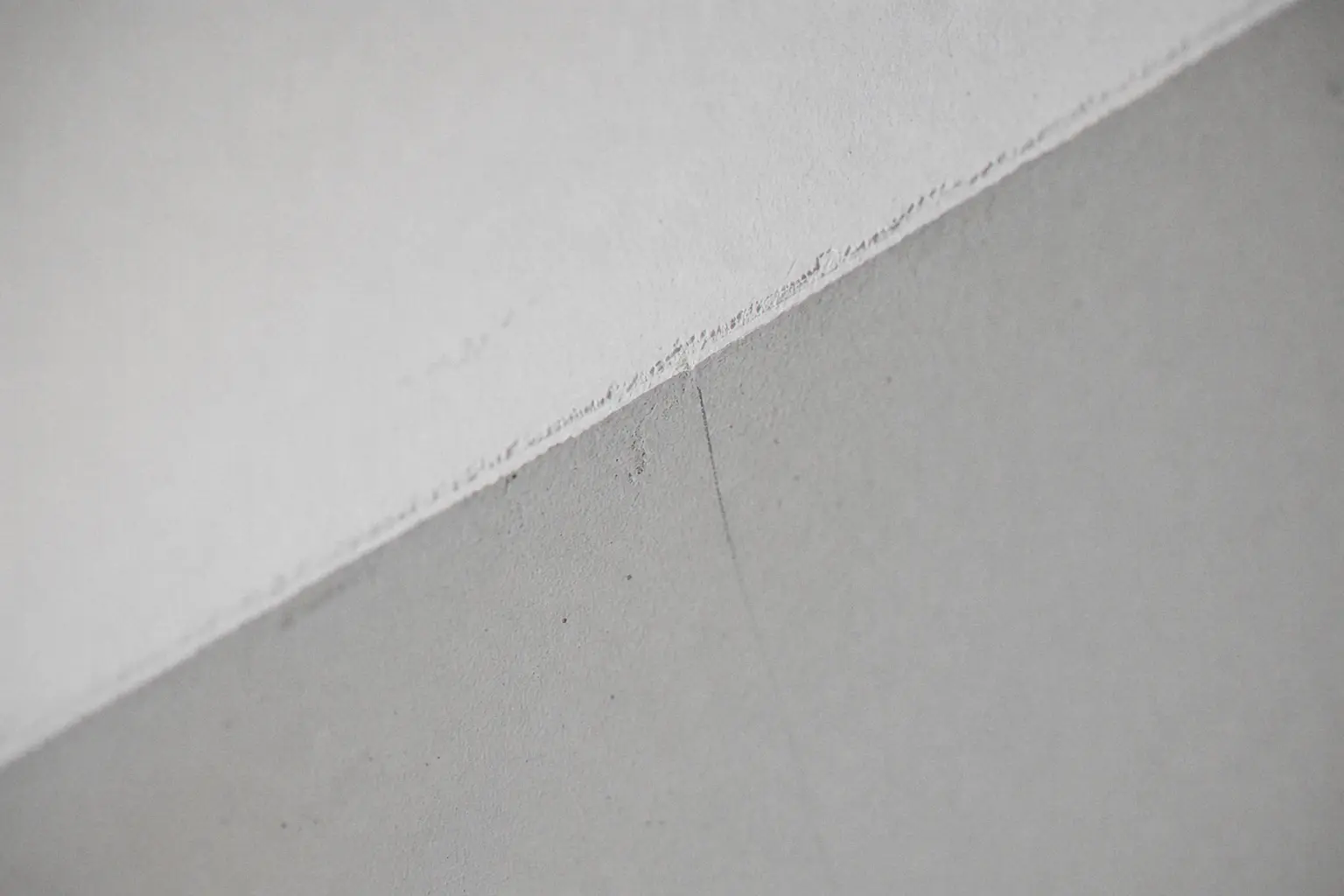 Arête nette entre un plafond blanc pur mat et un mur gris soie, coupe tirée au pinceau