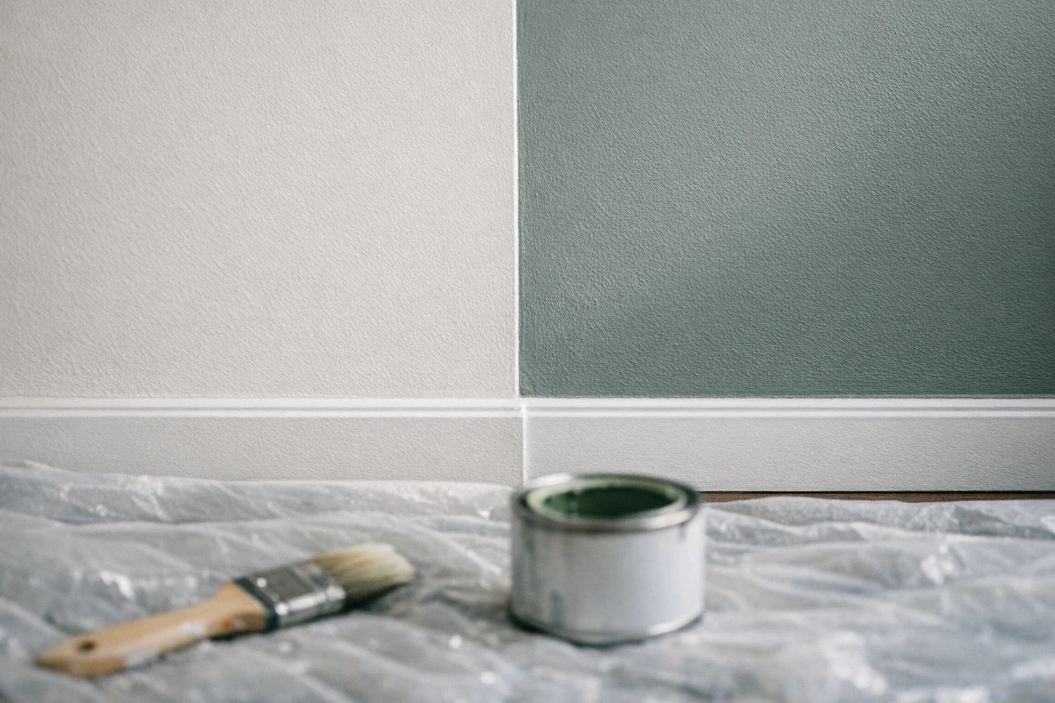 Détail d'un mur fraîchement peint en blanc cassé avec outils de peintre posés sur bâche