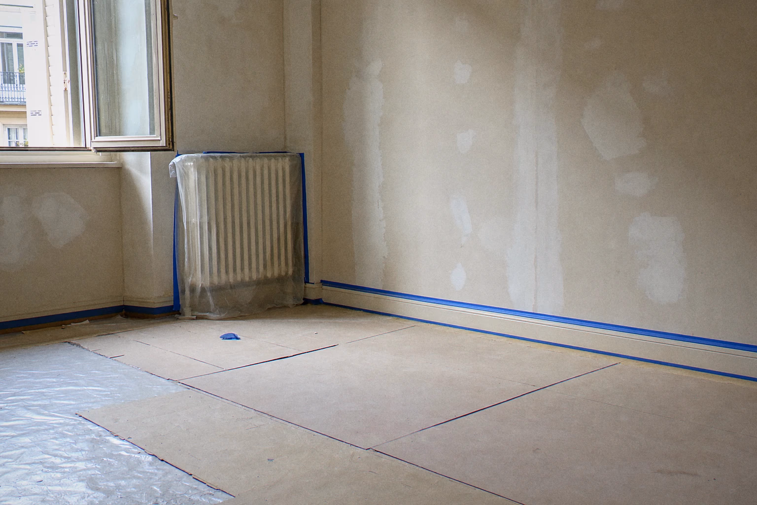Chantier de remise en état entre-baux à Genève — bâches au sol, menuiseries masquées, mur en cours : organisation Renovhome