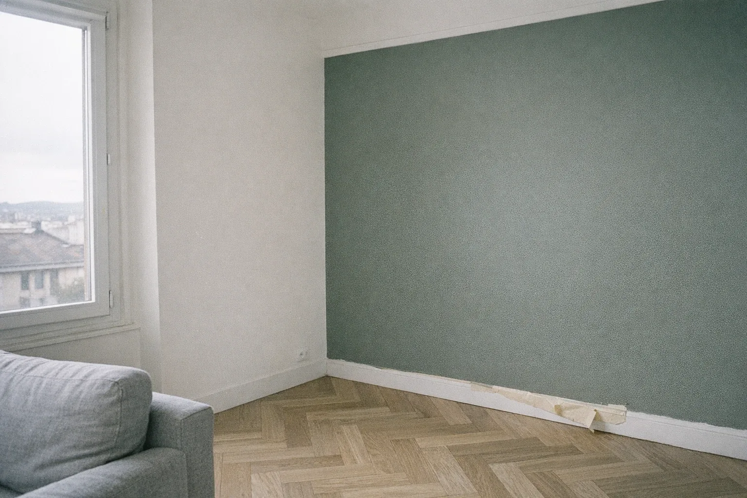 Séjour repeint avec un mur d’accent vert sauge profond, autres murs blanc cassé, parquet point de Hongrie