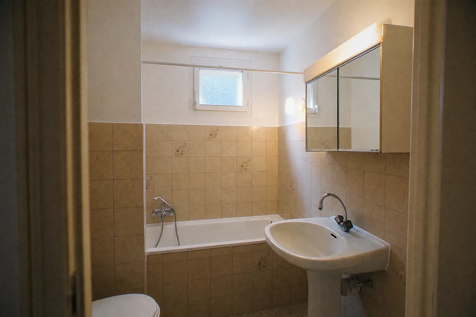 Salle de bain d'appartement locatif reprise après un dégât d'eau : plafond et hauts de murs repeints, carrelage d'origine conservé