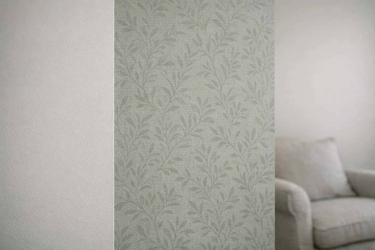Mur recouvert d'un papier peint intissé motif végétal vert sauge